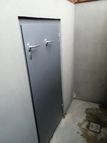 Installed flood-resistant exterior door at a below-grade entrance